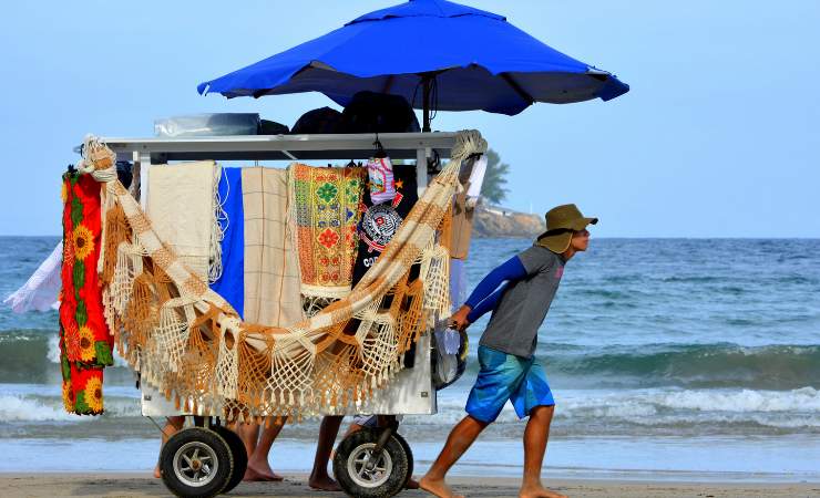 Venditore che trascina carretto sulla spiaggia