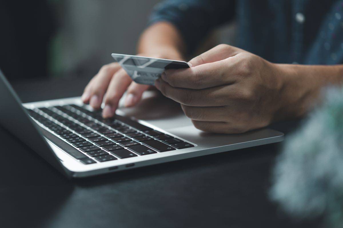Persona con carta di credito in mano e computer