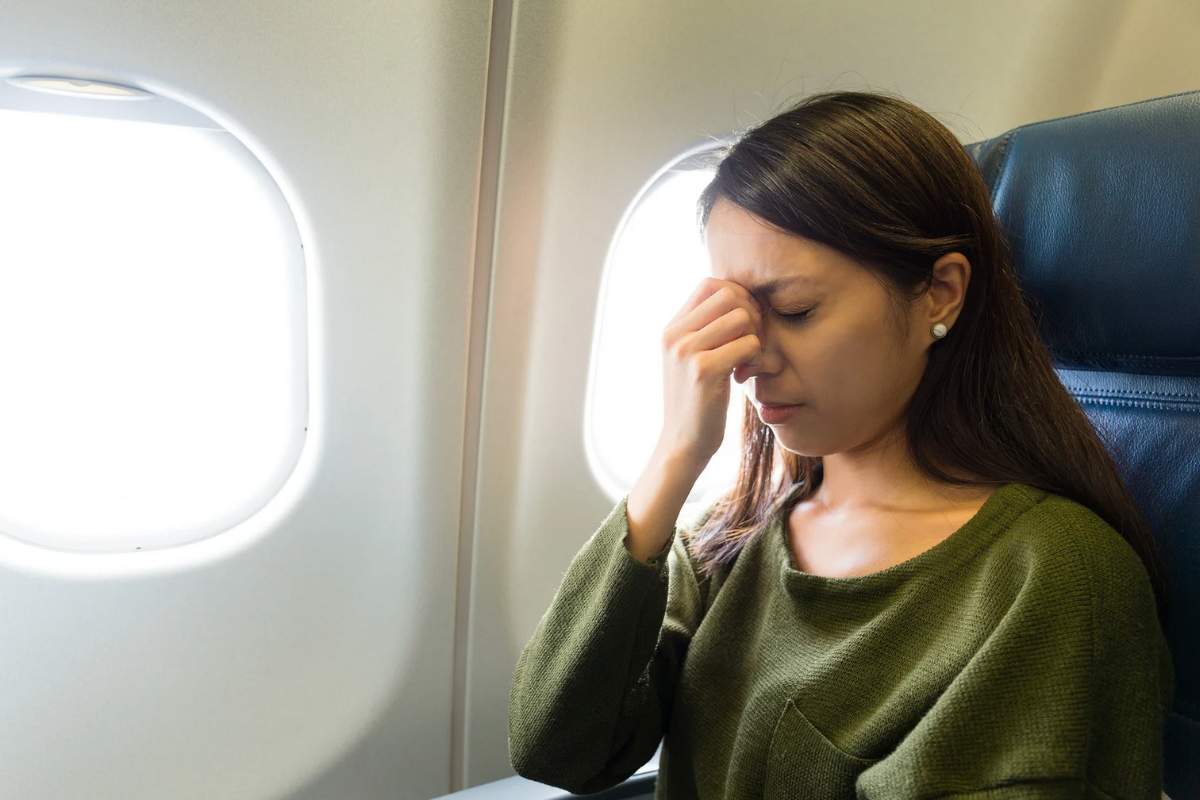 Donna in aereo che si stringe il naso con le dita