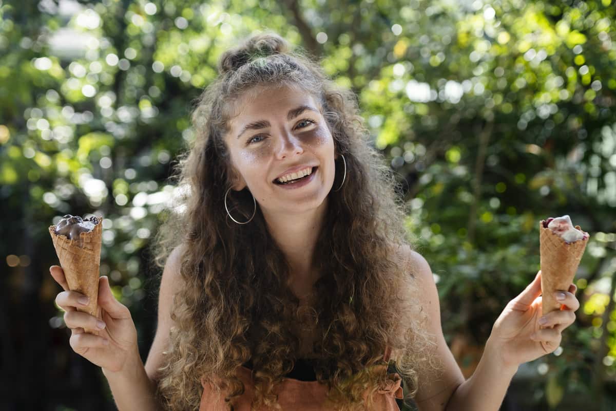 Ragazza sorridente che porta tra le mani due coni gelato