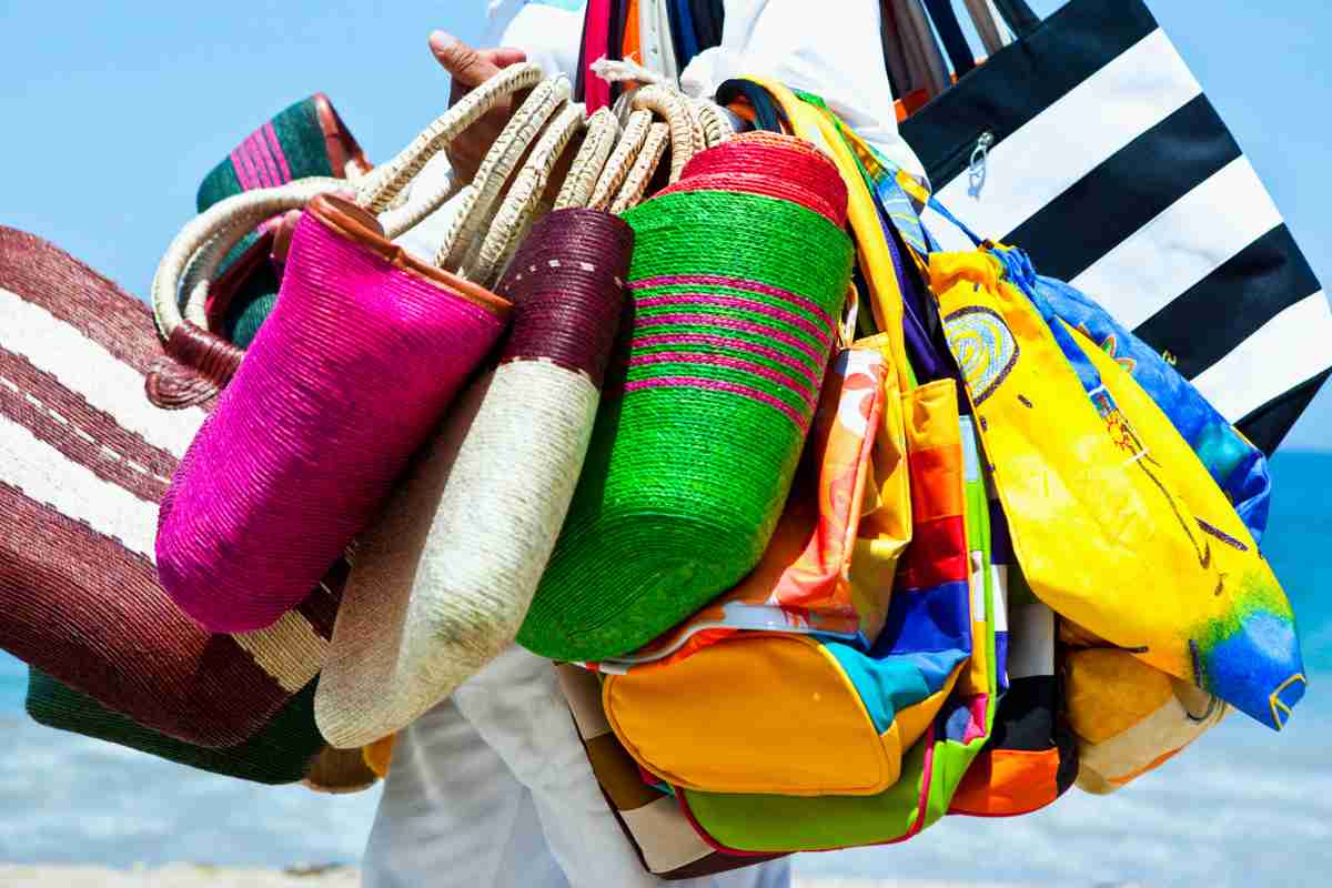 Venditore con borse sulla spiaggia