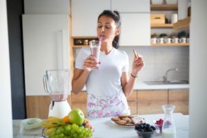 donna che beve e prepara frullato