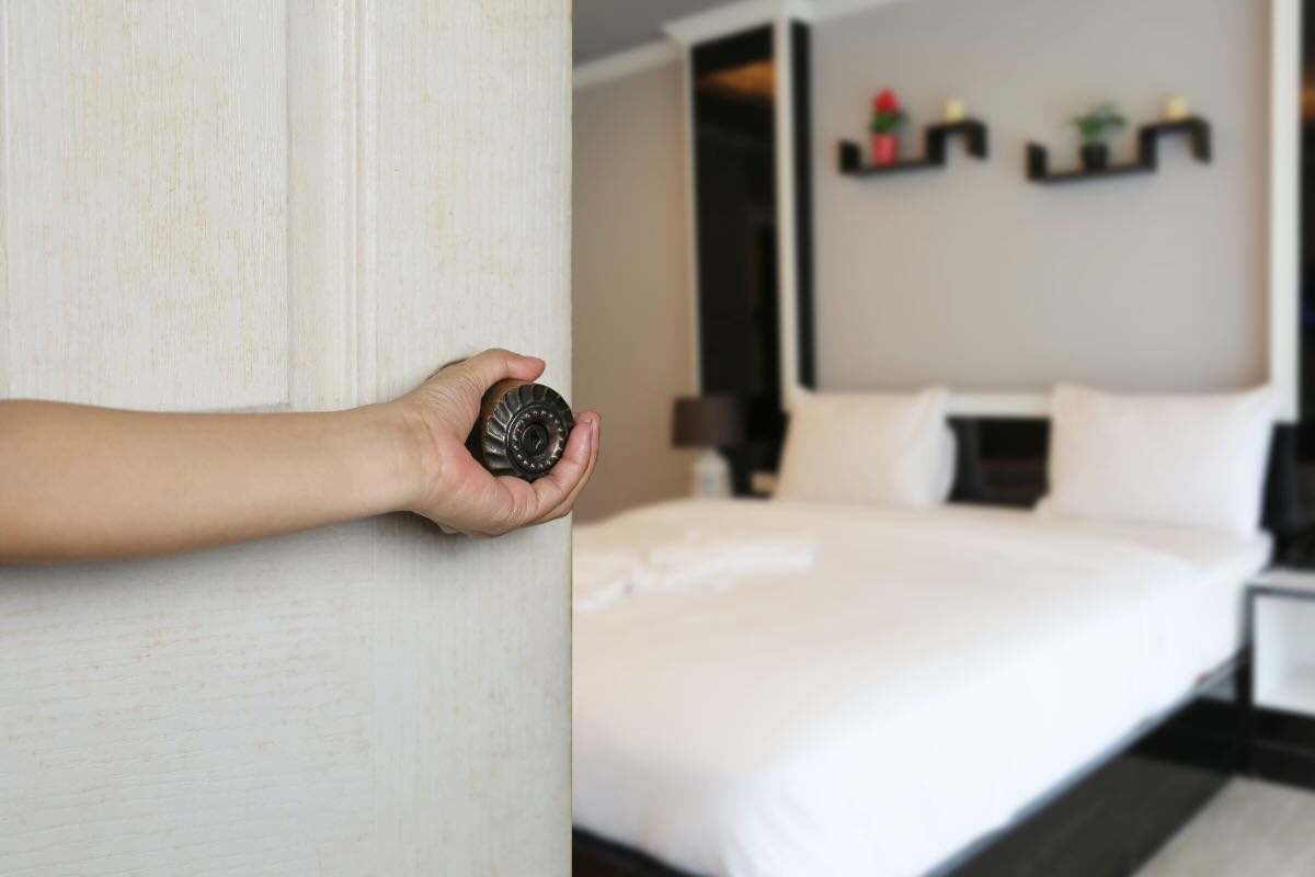 Persona che apre la porta di una camera da letto