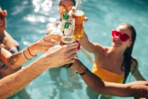 Ragazzi in piscina con birre in mano