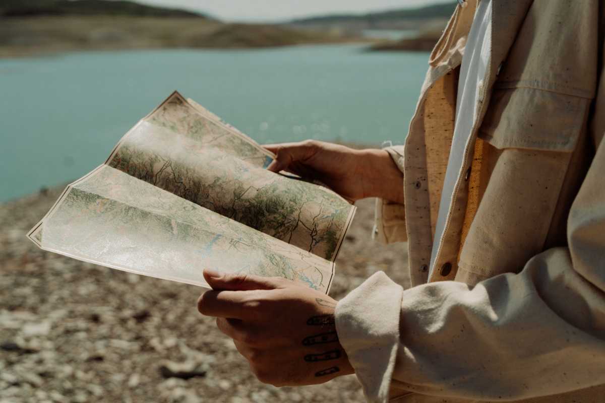 Persona con una mappa in mano e un lago sullo sfondo