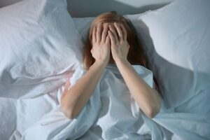 Donna nel letto con mani sul viso