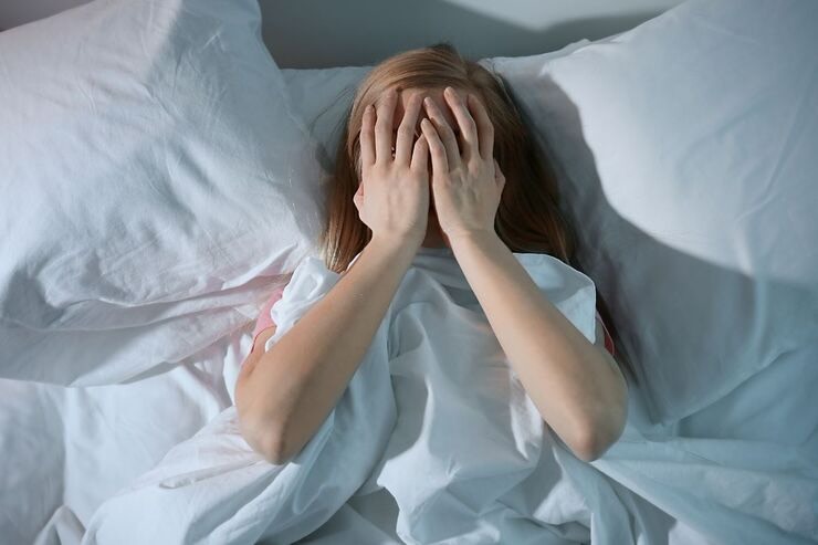 Donna nel letto con mani sul viso