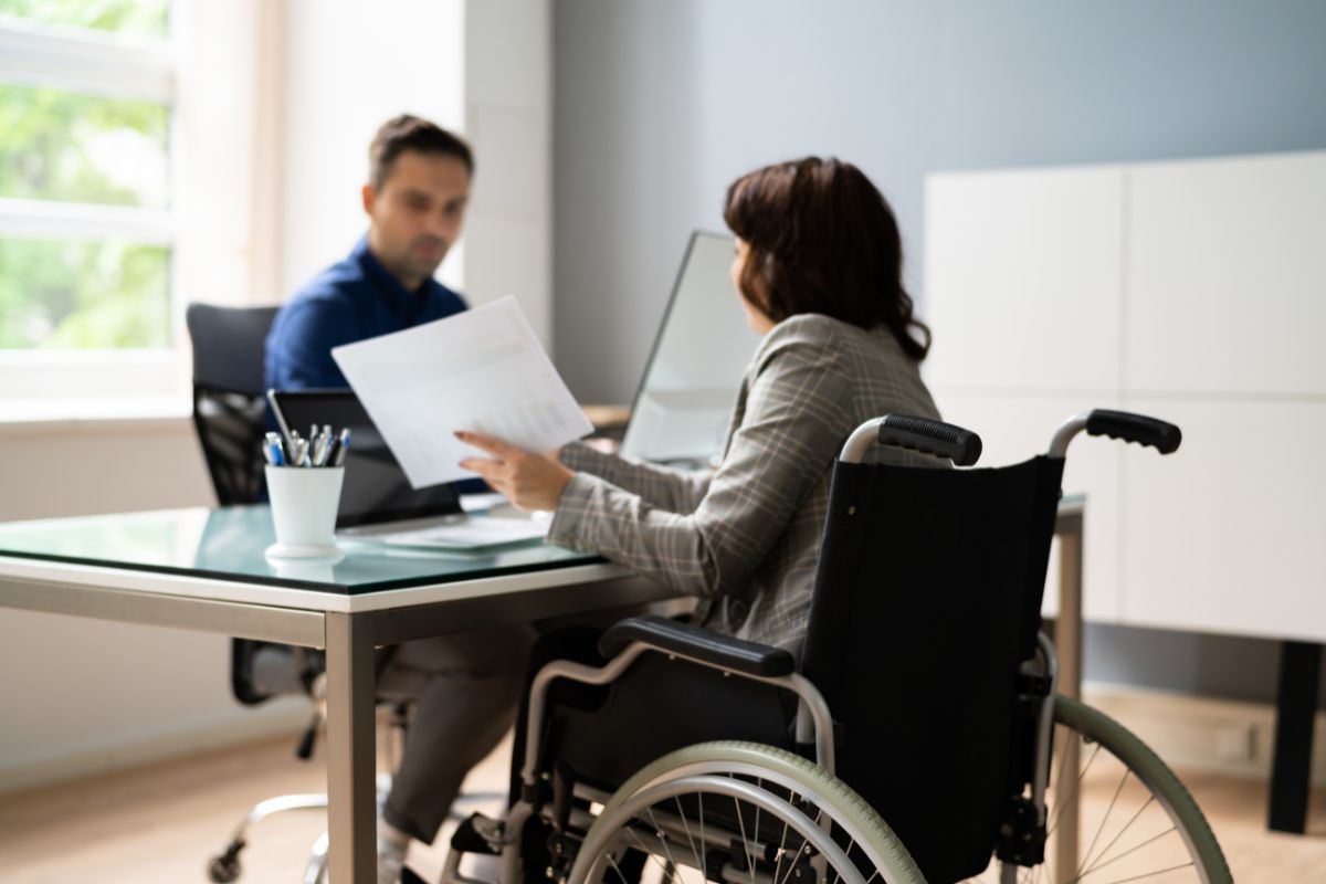 donna su sedia a rotelle al lavoro con collega ufficio